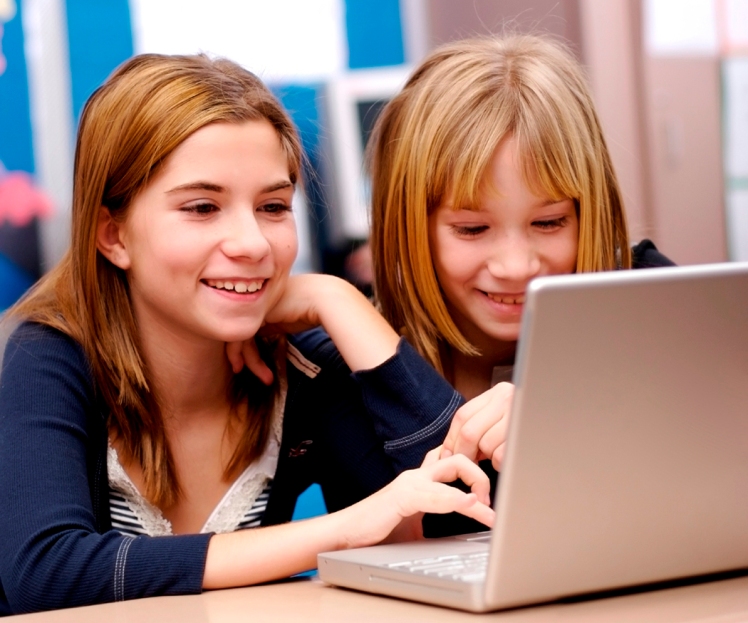 Two young girls working on a laptop in the classroom